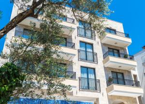 an apartment building with balconies and a tree at B&B Amfora in Petrovac na Moru