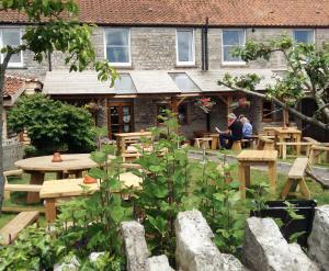 a group of people sitting at tables in a garden at Cross Keys Inn in East Lydford