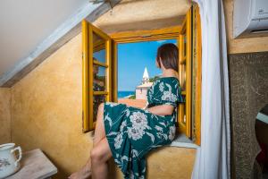 a woman sitting on a window looking out at the ocean at La Dolce Vita Residence - Romantic Boutique Stay for Couples, Veli Lošinj Old Town in Veli Lošinj