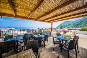 d'une terrasse avec tables et chaises et vue sur l'océan. dans l'établissement Casa Papiro, à Lipari