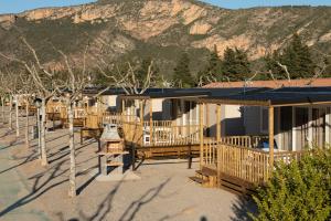 una fila de casas con árboles y montañas en el fondo en La Noguera Camping, en Sant Llorenç de Montgai