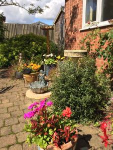 un jardín con flores y una estatua frente a una casa en The Buttery en Brundall