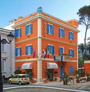 um edifício laranja com janelas azuis numa rua em Hotel L'Isola em Santa Marinella