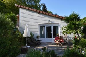 ein Cottage mit Stühlen und einem Sonnenschirm auf einer Terrasse in der Unterkunft Dans un jardin in Apremont-la-Forêt