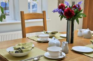 einen Holztisch mit einer Blumenvase darauf in der Unterkunft The Swallows Rest Bed & Breakfast in Brigstock