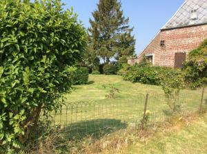 an old brick house with a fence in a yard at Gite a la campagne in Mailly-Maillet