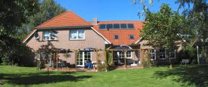 a large brick house with a lawn in front of it at Pension Am Wiesengrund in Detern