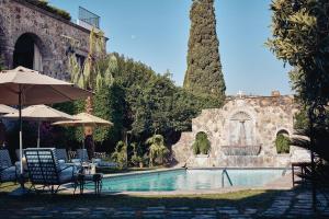 a pool with chairs and umbrellas next to a building at Casa de Sierra Nevada, A Belmond Hotel, San Miguel de Allende in San Miguel de Allende