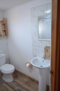 a white bathroom with a toilet and a sink at Cabaña Laynaturi in San Pedro de Atacama