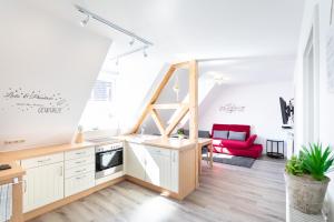 a kitchen with white cabinets and a red couch at Ferienwohnung Mittendrin in Baunach
