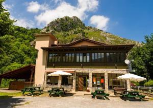 um edifício com mesas de piquenique em frente a uma montanha em Hotel del Alto Sella em Amieva