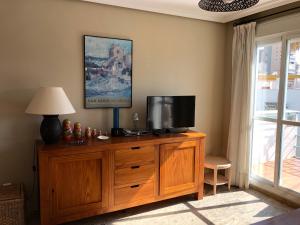 a living room with a television on a wooden dresser at RESIDENCIAL DON PEDRO in Torremolinos
