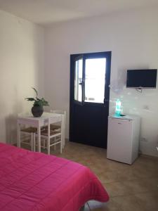 a room with a bed and a door and a table at Il Ginepro in Valledoria