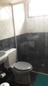 a bathroom with a toilet, sink, and tub at Pousada Sognares in Guarulhos