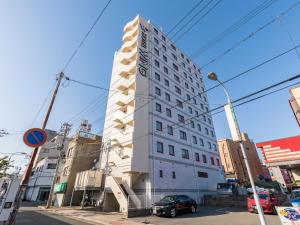 un edificio blanco alto en una calle de la ciudad con coches en Hotel Wing International Shimonoseki, en Shimonoseki