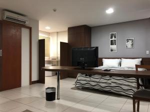 Summit Dom Apart Hotel في لورينا: غرفة بها مكتب مع تلفزيون وسرير