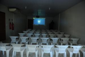 a room filled with white chairs and a screen at Hotel Kanaan in Pimenta Bueno
