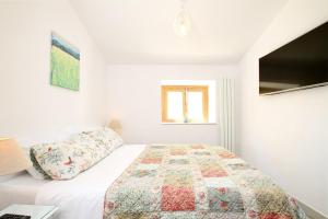 a white bedroom with a bed and a tv at Pollenca Townhouse in Pollença