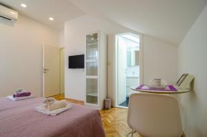 Cette chambre comprend deux lits, une chaise et un miroir. dans l'établissement Apartman Split Old Town Center, à Split
