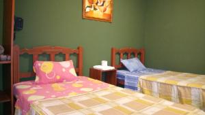 2 camas en una habitación con paredes verdes en Hostal Residencial Mochica, en Lima