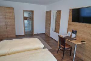 1 dormitorio con 1 cama y escritorio con TV en Gästehaus Aßlschwang, en Freystadt