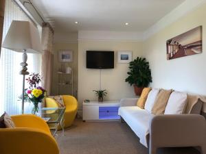 a living room with a couch and a tv at Arun Sands Rooms in Littlehampton