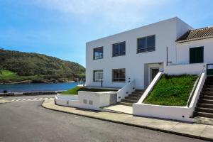 una casa blanca con escaleras y un río en Monte da Guia en Horta