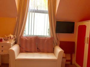 a white couch with a pillow in front of a window at Arun Sands Rooms in Littlehampton