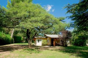 a small yellow house with a tree in the yard at Del Arroyo Cabañas in Villa General Belgrano