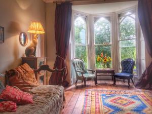 a living room with a couch and chairs and windows at 84 Saint Andrews Road in Bridport