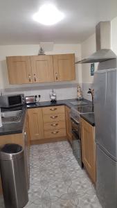 a kitchen with wooden cabinets and a stainless steel refrigerator at Chinwin Cottage in Weymouth