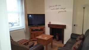 sala de estar con TV y chimenea en Chinwin Cottage, en Weymouth