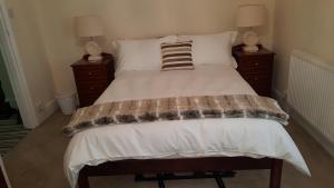 łóżko w sypialni z 2 stolikami nocnymi i 2 lampami w obiekcie Chinwin Cottage w mieście Weymouth