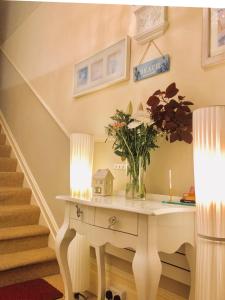 a room with a table with a vase of flowers on it at Arun Sands Rooms in Littlehampton