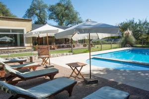 a swimming pool with chairs and umbrellas next to a swimming pool at Del Arroyo Cabañas in Villa General Belgrano
