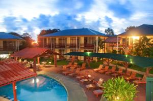 a hotel with a pool and chairs and a building at Amapola Resort in Jacó