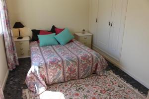 a bedroom with a bed with colorful sheets and pillows at Cozy Summer House by the Beach in Ovar