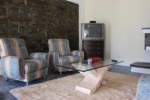 a living room with two chairs and a tv at Cozy Summer House by the Beach in Ovar