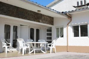 a patio with white chairs and a table at Cozy Summer House by the Beach in Ovar