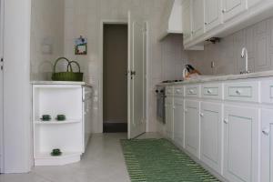 a kitchen with white cabinets and a green rug at Cozy Summer House by the Beach in Ovar
