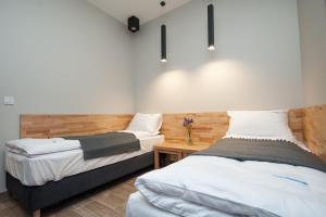 a bedroom with two beds and a wooden wall at Dream Team Nordic Haven in Bydgoszcz