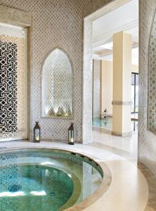 a bath tub sitting inside of a bathroom next to a pool at Four Seasons Resort Marrakech in Marrakech