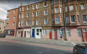 a woman walking down a sidewalk in front of a building at Slateford House Apartment Ground Floor Main Door in Edinburgh