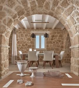 comedor con paredes de piedra, mesa y sillas en Arismari Luxury Villas en Vasilikos