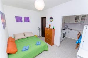 a bedroom with a green bed and a kitchen at House Filip in Bogomolje