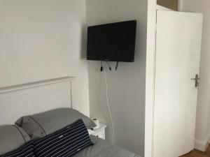 a flat screen tv hanging on a wall in a bedroom at Charimore Relaxation House in Abbey Wood