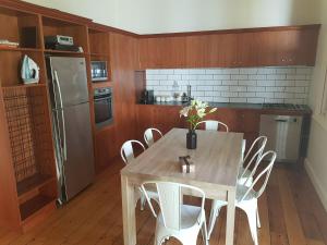 a kitchen with a wooden table and white chairs at Myers CBD in Bendigo
