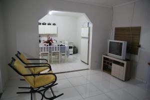 a living room with a tv and a chair and a kitchen at Casa de Temporada na Orla in Canindé de São Francisco