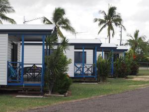 a blue and white house with palm trees at Bowen Holiday Park in Bowen