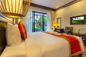 a bedroom with a large white bed and a living room at Hoi An Field Boutique Resort & Spa in Hoi An